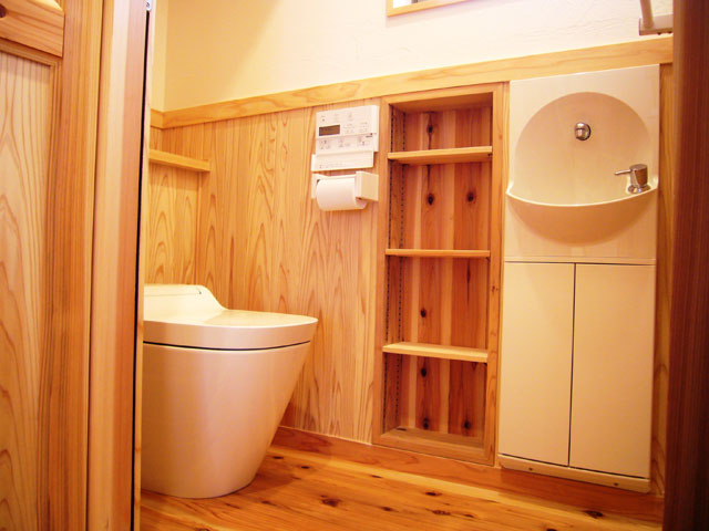 ３か所あるトイレ。いつもの杉の腰板と漆喰の壁に加え棚板を装備、さらに既製品の手洗い収納をビルトインで省スペース。