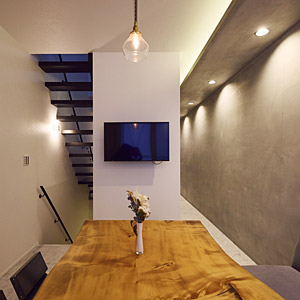 ダイニングテーブルは木製でコンクリートの壁と異素材を組み合わせながらも落ち着いた空間に